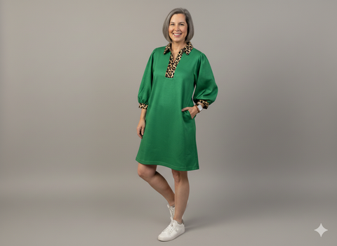 Woman wearing a green dress with leopard print accents on a gray background